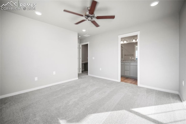 unfurnished bedroom with ensuite bathroom, ceiling fan, and light colored carpet