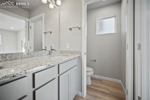 bathroom with hardwood / wood-style floors, vanity, and toilet