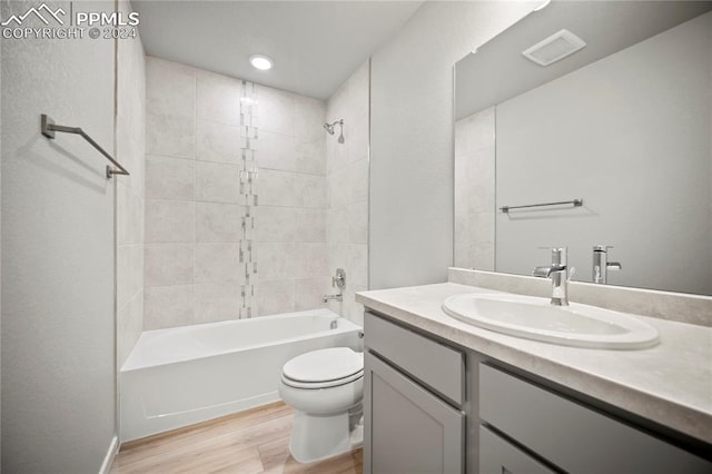 full bathroom featuring wood-type flooring, vanity, toilet, and tiled shower / bath