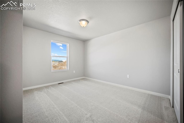 carpeted empty room featuring a textured ceiling