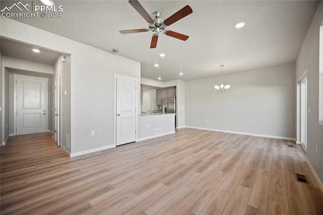 unfurnished living room featuring ceiling fan with notable chandelier and light wood-type flooring