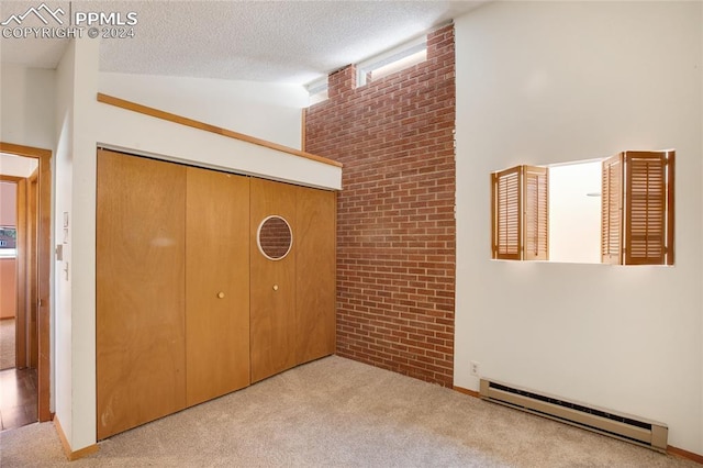 unfurnished bedroom with light carpet, a closet, brick wall, and a baseboard heating unit