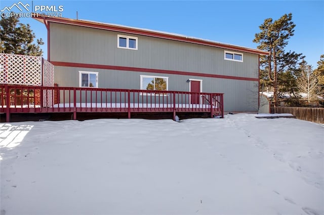 snow covered rear of property with a wooden deck