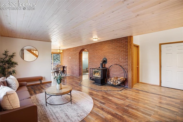 living room featuring a wood stove, wooden ceiling, wood-type flooring, and an inviting chandelier