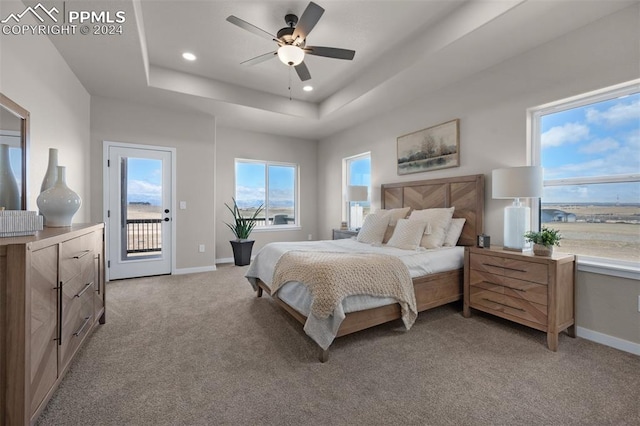 carpeted bedroom with access to outside, a raised ceiling, and ceiling fan