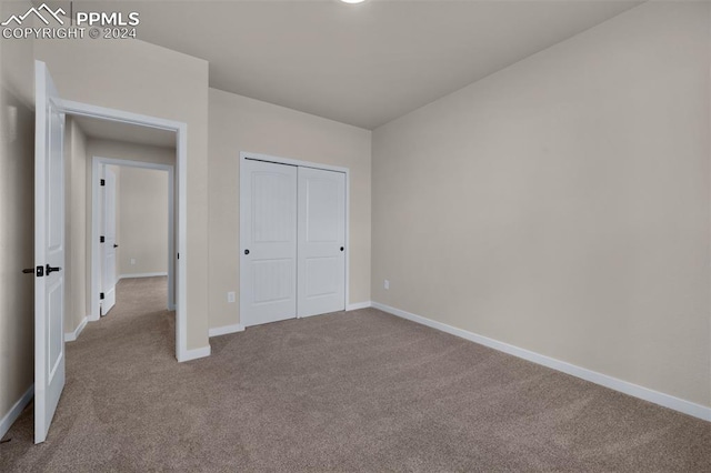 unfurnished bedroom featuring a closet and light colored carpet