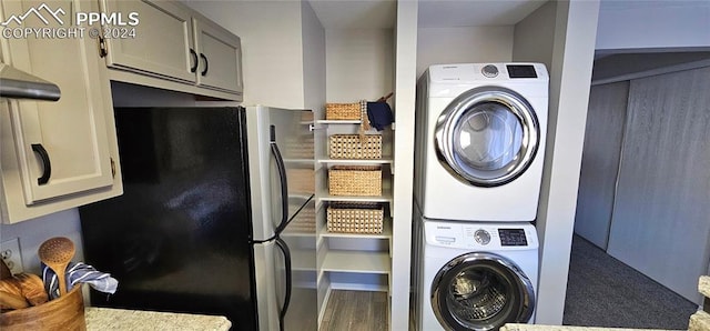 laundry room featuring hardwood / wood-style floors and stacked washer / drying machine