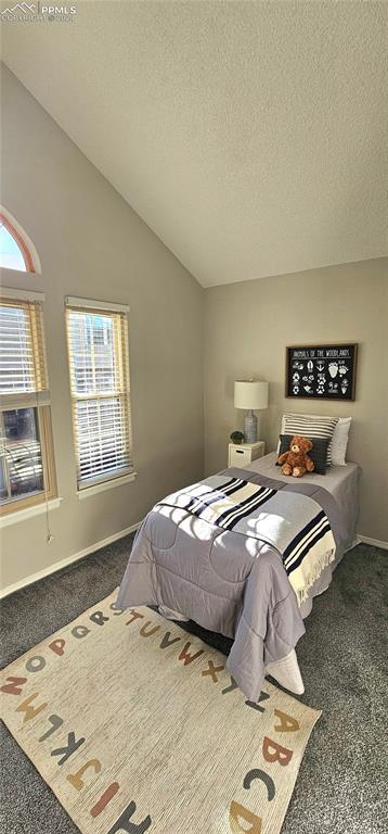 bedroom with dark carpet, lofted ceiling, and a textured ceiling