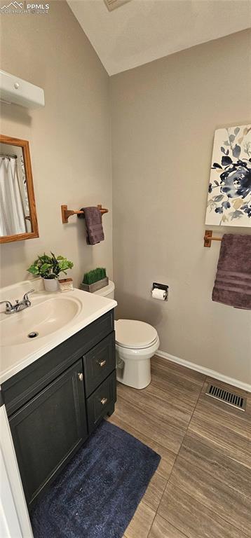 bathroom featuring tile patterned floors, vanity, toilet, and vaulted ceiling