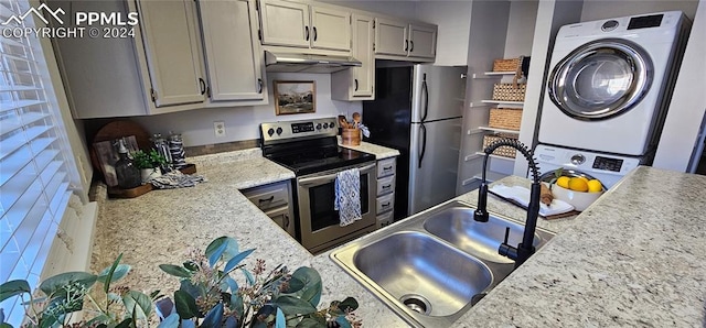 kitchen with gray cabinetry, sink, stacked washer and dryer, and stainless steel appliances