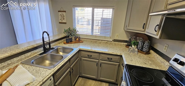 kitchen featuring kitchen peninsula, light stone countertops, sink, and stainless steel range with electric cooktop