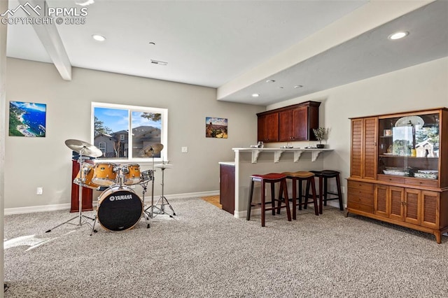 kitchen featuring beamed ceiling, a breakfast bar, light colored carpet, and kitchen peninsula