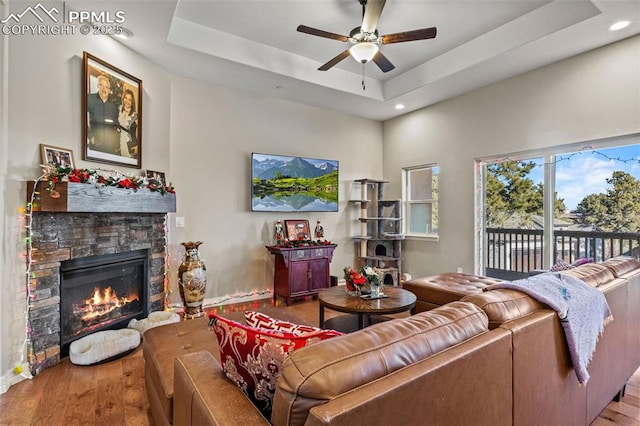 living room featuring a raised ceiling, ceiling fan, a fireplace, and hardwood / wood-style flooring