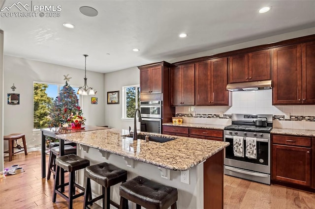 kitchen featuring a center island with sink, decorative light fixtures, appliances with stainless steel finishes, and a chandelier