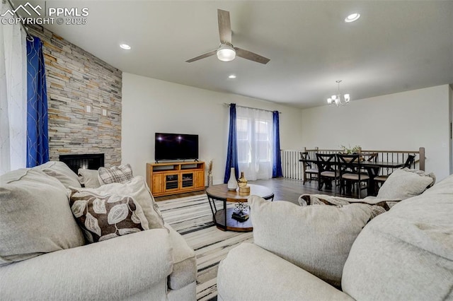 living room featuring a fireplace, ceiling fan with notable chandelier, and hardwood / wood-style flooring