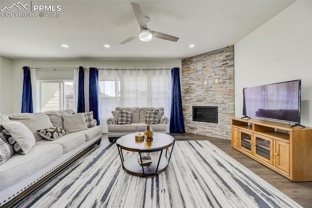 living room featuring ceiling fan, a fireplace, and hardwood / wood-style flooring