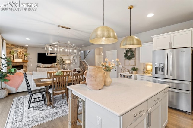 kitchen featuring pendant lighting, white cabinetry, a kitchen island, and stainless steel fridge with ice dispenser