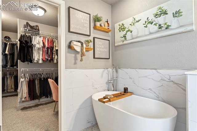 bathroom featuring a washtub and tile walls