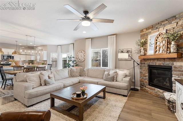 living room with ceiling fan, a fireplace, and light hardwood / wood-style floors