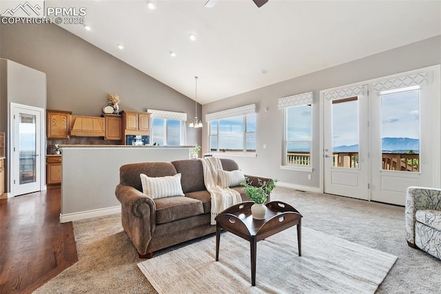 carpeted living room featuring high vaulted ceiling, a healthy amount of sunlight, and ceiling fan with notable chandelier