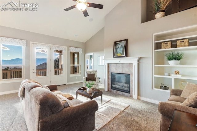 carpeted living room featuring a tile fireplace, ceiling fan, built in features, and high vaulted ceiling