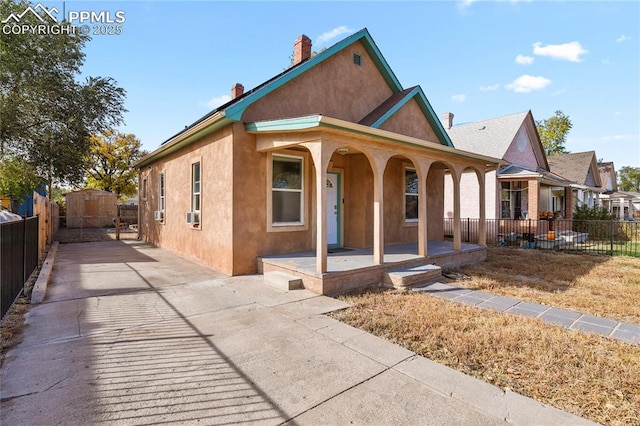 view of front of property featuring covered porch and a shed