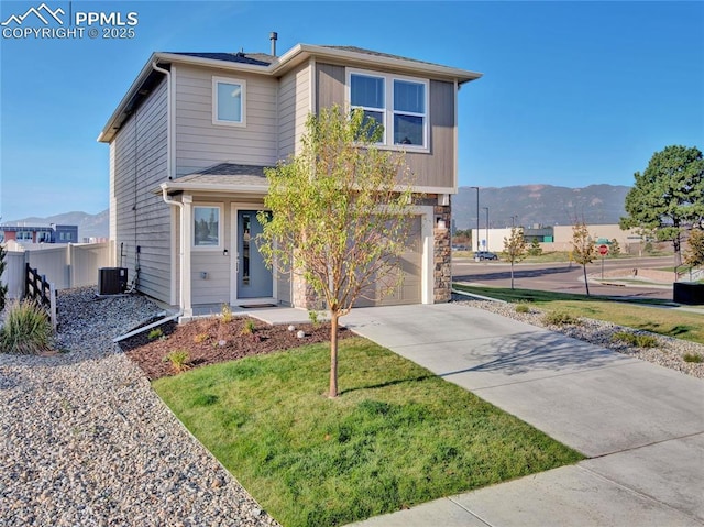 view of front of house with a garage, a mountain view, a front lawn, and central air condition unit