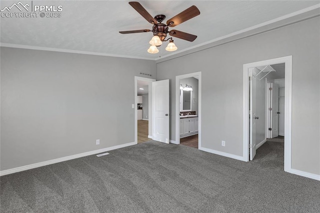 unfurnished bedroom with ornamental molding, ceiling fan, sink, dark colored carpet, and connected bathroom