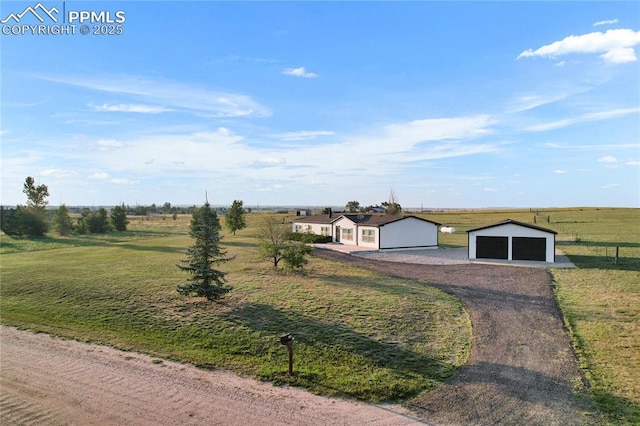 single story home featuring a front lawn, a rural view, an outdoor structure, and a garage