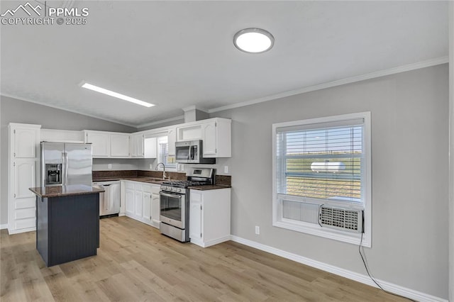 kitchen with appliances with stainless steel finishes, light hardwood / wood-style flooring, white cabinets, a kitchen island, and lofted ceiling