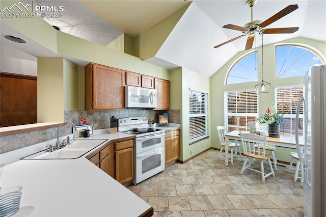 kitchen featuring white appliances, vaulted ceiling, sink, decorative light fixtures, and backsplash