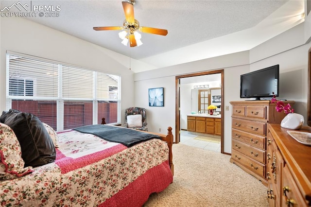 carpeted bedroom featuring lofted ceiling, ensuite bath, a textured ceiling, and ceiling fan