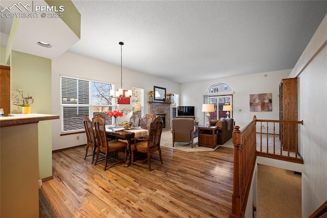 dining area with a brick fireplace, an inviting chandelier, and hardwood / wood-style floors