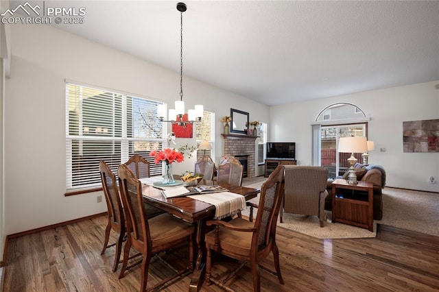 dining space with wood-type flooring, a fireplace, and an inviting chandelier