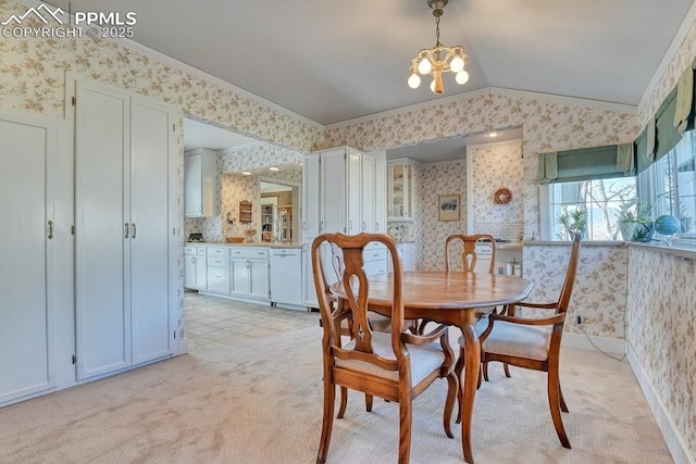 dining space with a chandelier, light colored carpet, vaulted ceiling, and crown molding