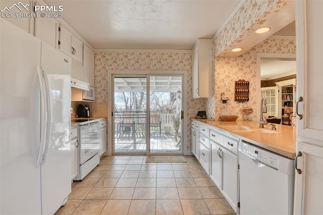 kitchen featuring a textured ceiling, white appliances, sink, white cabinetry, and light tile patterned flooring