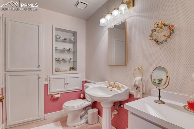 bathroom featuring built in shelves, toilet, and sink