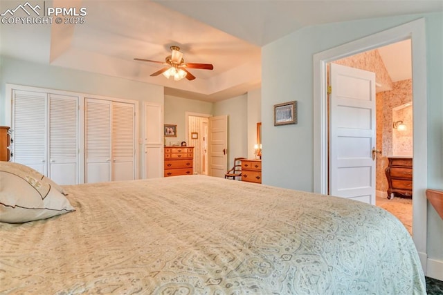 bedroom with two closets, a tray ceiling, and ceiling fan