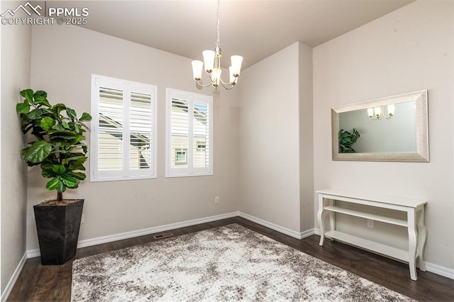 empty room with dark hardwood / wood-style floors and a notable chandelier