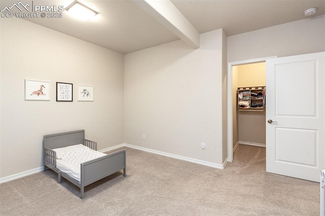 carpeted bedroom featuring beam ceiling, a spacious closet, and a closet