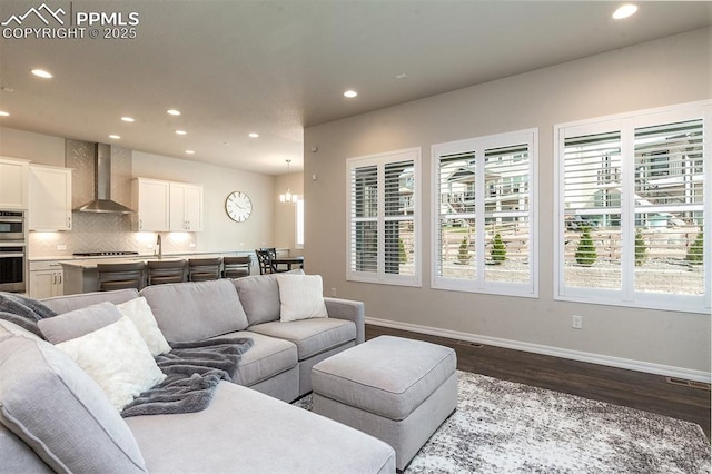 living room with hardwood / wood-style floors, a notable chandelier, and sink