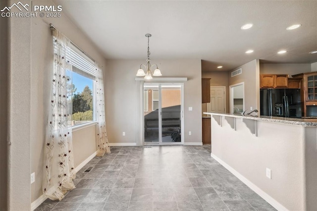 kitchen featuring black refrigerator with ice dispenser, kitchen peninsula, a chandelier, decorative light fixtures, and a breakfast bar area