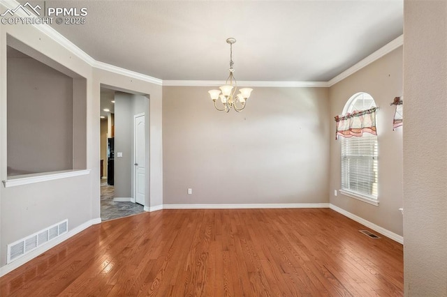 empty room with hardwood / wood-style flooring, an inviting chandelier, and crown molding