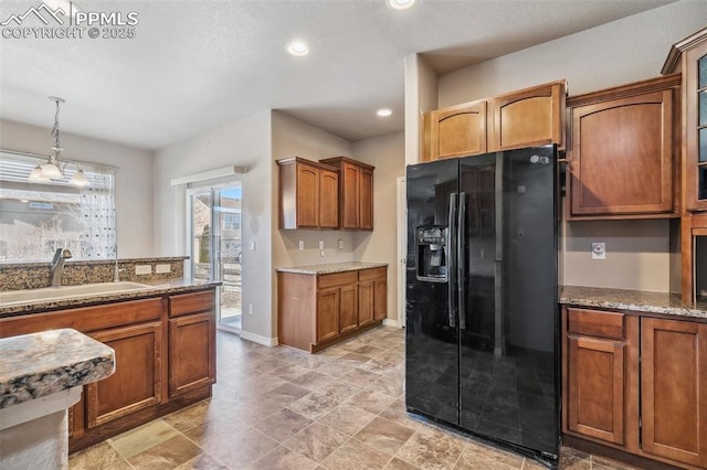 kitchen with black fridge, sink, hanging light fixtures, and a notable chandelier