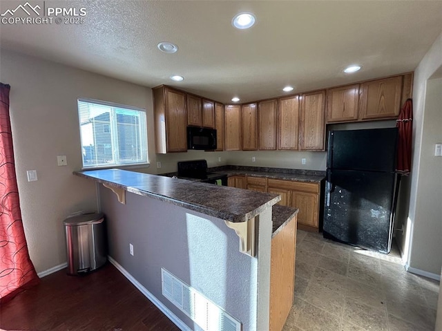 kitchen featuring black appliances, a kitchen breakfast bar, and kitchen peninsula