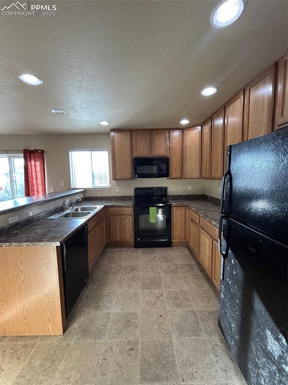 kitchen featuring kitchen peninsula, sink, a healthy amount of sunlight, and black appliances