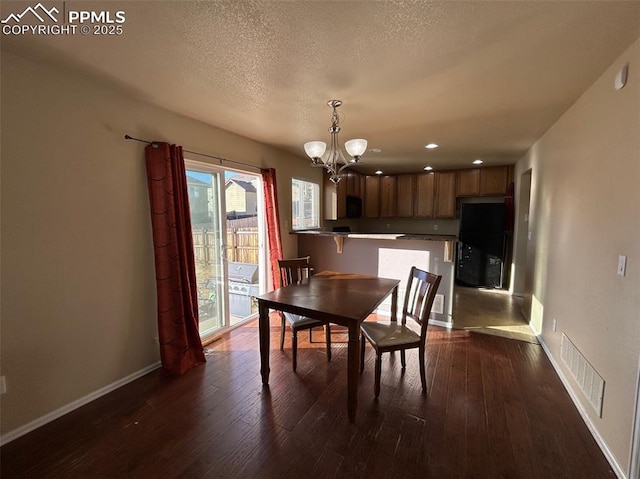 unfurnished dining area featuring dark wood-type flooring, a textured ceiling, and an inviting chandelier