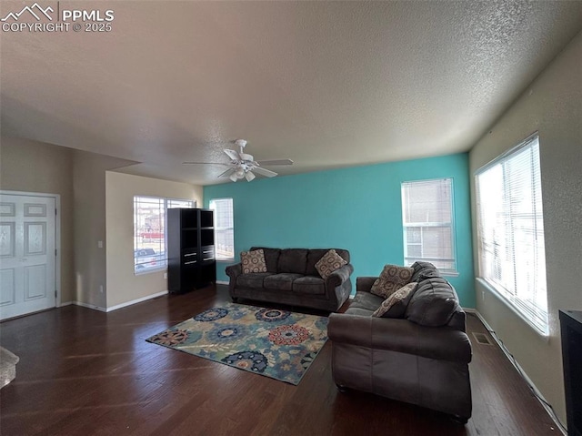 living room with ceiling fan, dark wood-type flooring, and a textured ceiling