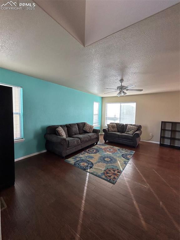 living room featuring a textured ceiling, dark hardwood / wood-style floors, and ceiling fan