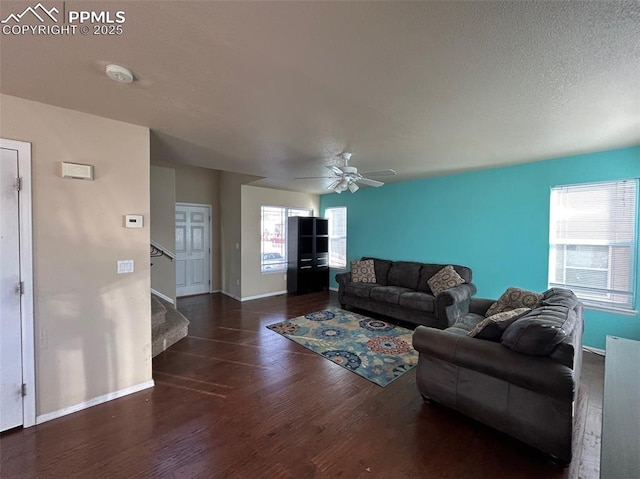 living room with ceiling fan, dark wood-type flooring, and a textured ceiling